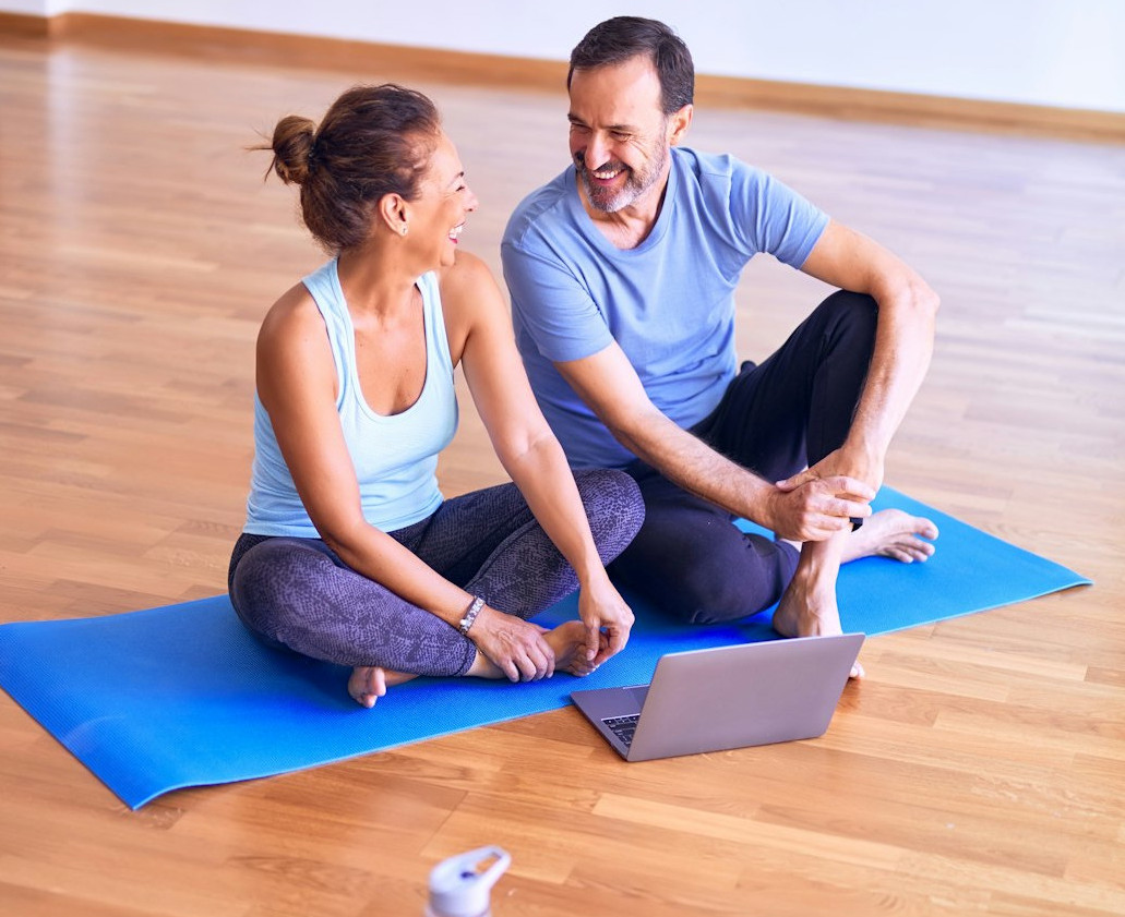 man in white tank top and gray pants sitting on blue yoga mat